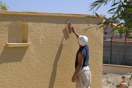 un travailleur qui termine les derniers travaux de peinture sur un mur extérieur